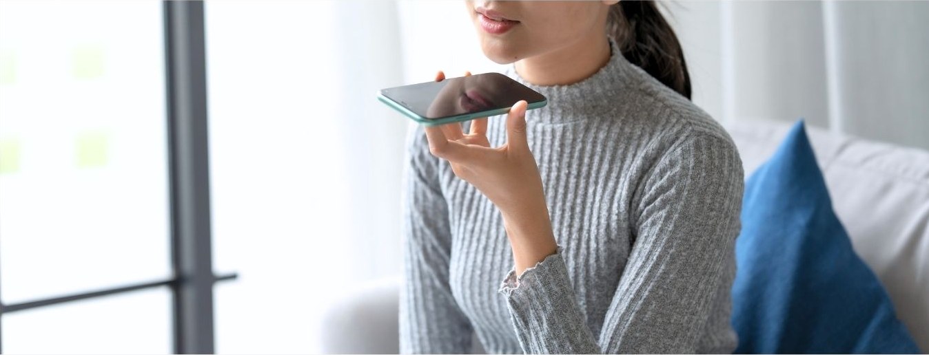 スマートフォンに話しかけて検索する女性